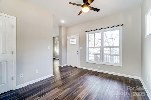 interior space with dark wood-style floors, visible vents, baseboards, and a ceiling fan