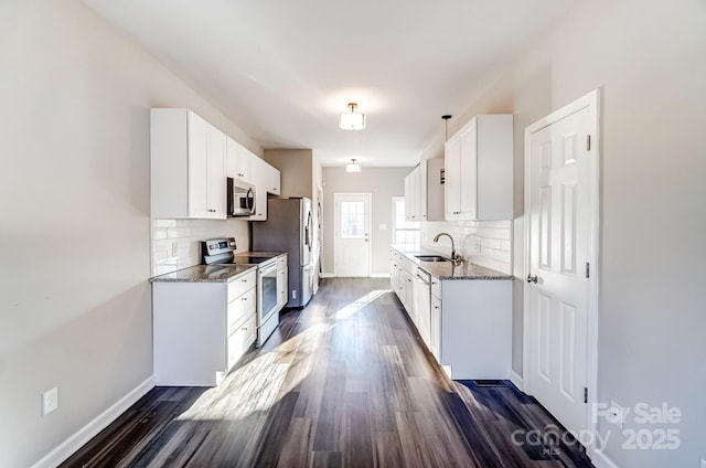 kitchen with dark stone counters, appliances with stainless steel finishes, a sink, and white cabinetry