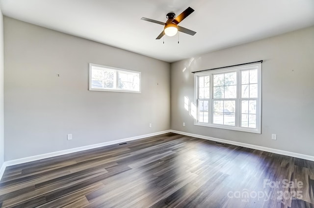 empty room with ceiling fan, dark wood-type flooring, visible vents, and baseboards