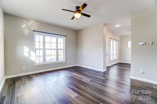 spare room with dark wood-style floors, a ceiling fan, and baseboards