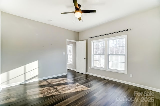 unfurnished room with dark wood-type flooring, visible vents, baseboards, and a ceiling fan