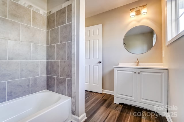 bathroom with shower / bathtub combination, wood finished floors, vanity, and baseboards