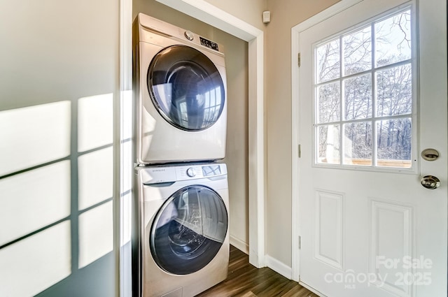 washroom with dark wood-style floors, laundry area, stacked washer / dryer, and baseboards