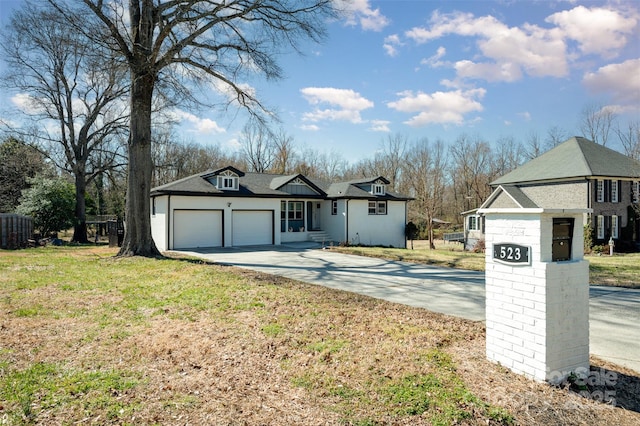 view of front of home featuring an attached garage, concrete driveway, and a front yard