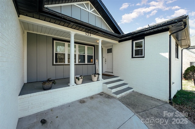 property entrance with covered porch, brick siding, and board and batten siding