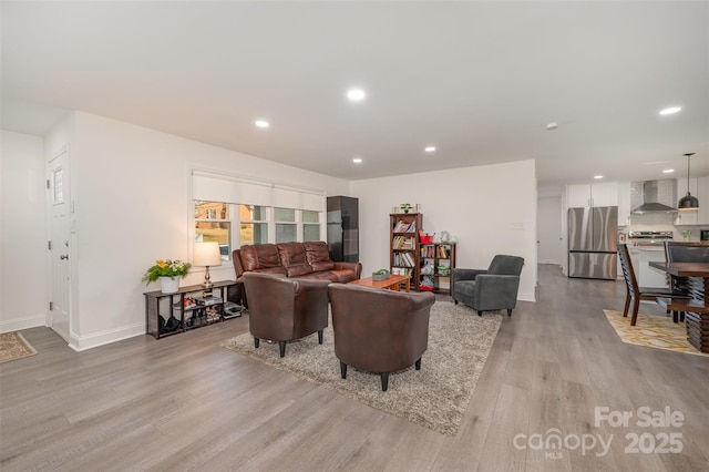 living area featuring baseboards, light wood finished floors, and recessed lighting