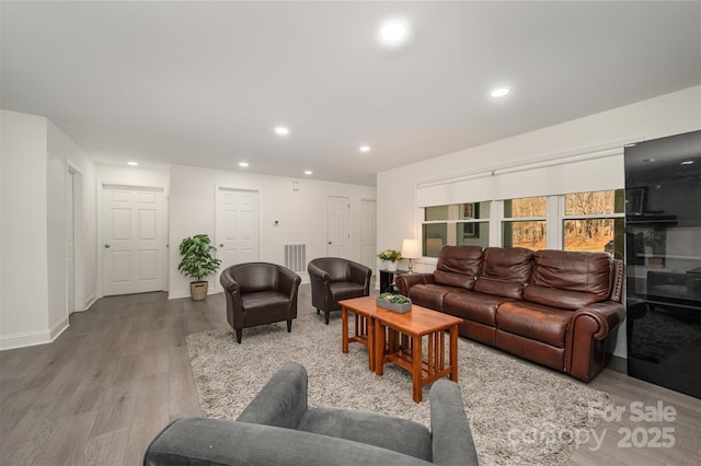 living area featuring light wood-style flooring, baseboards, and recessed lighting