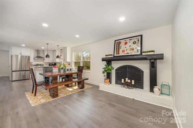 dining room with baseboards, a fireplace, wood finished floors, and recessed lighting