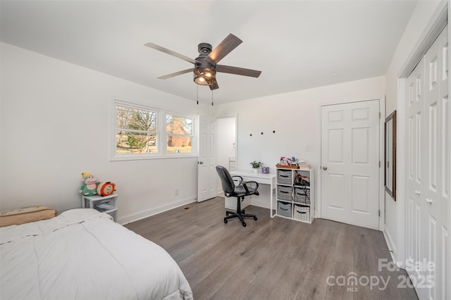 bedroom with a ceiling fan, a closet, baseboards, and wood finished floors