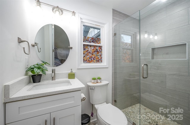 bathroom with a stall shower, vanity, and toilet