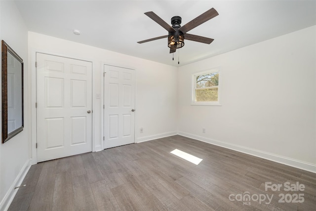 unfurnished bedroom featuring a ceiling fan, baseboards, and wood finished floors