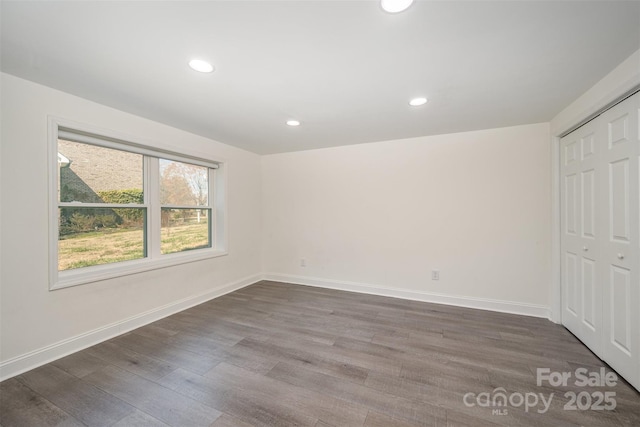 unfurnished bedroom featuring a closet, baseboards, dark wood-style flooring, and recessed lighting