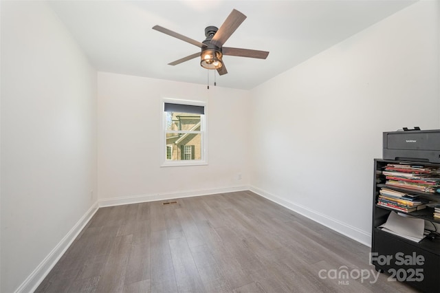 spare room featuring ceiling fan, visible vents, baseboards, and wood finished floors