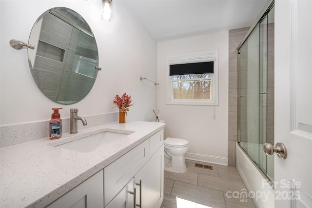 bathroom featuring baseboards, visible vents, bath / shower combo with glass door, toilet, and vanity