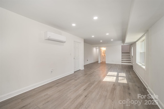 spare room with light wood-style flooring, recessed lighting, baseboards, stairs, and a wall mounted air conditioner