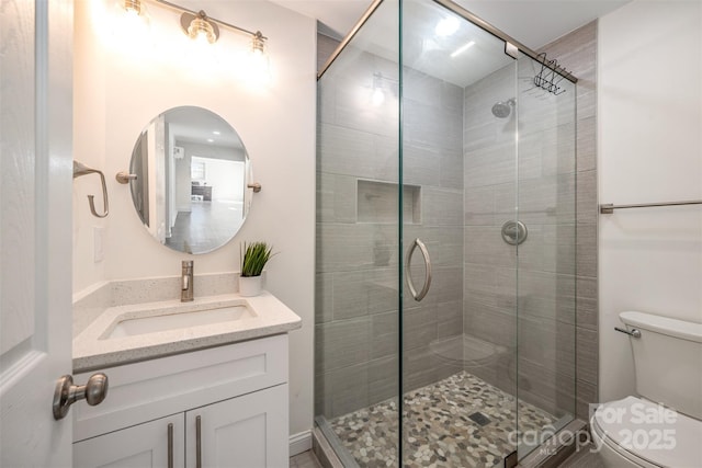 full bath featuring a stall shower, vanity, and toilet