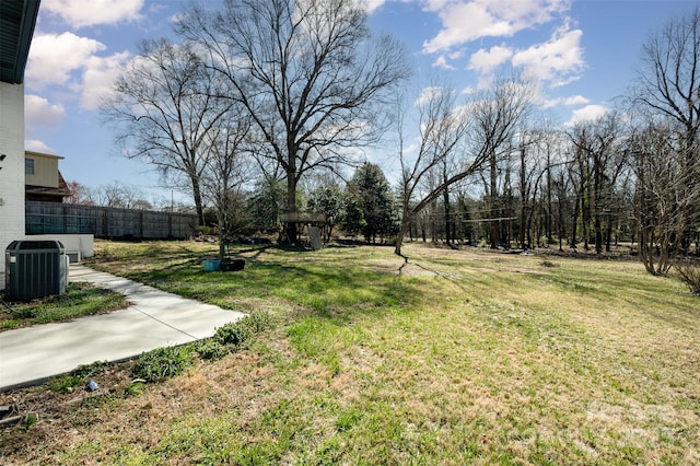 view of yard featuring central AC and fence