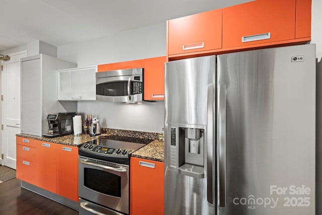 kitchen featuring appliances with stainless steel finishes, dark stone counters, and dark wood-style flooring