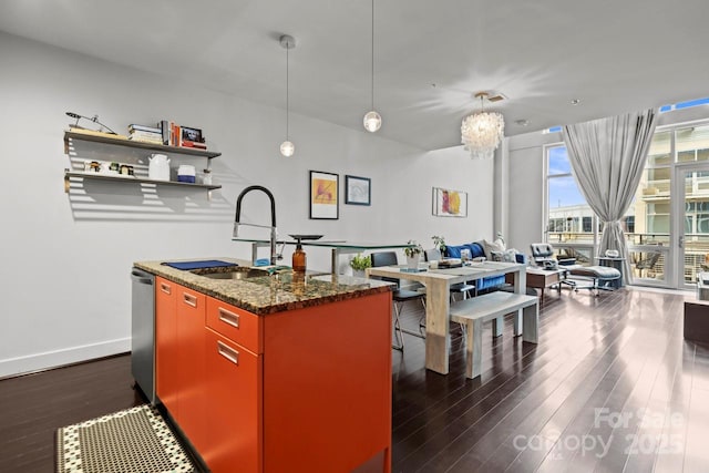 kitchen with a center island with sink, baseboards, dark wood finished floors, dishwasher, and a sink