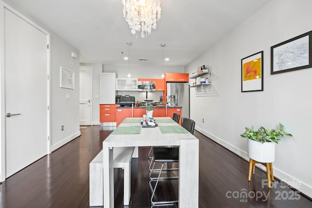 dining room with dark wood-style flooring, an inviting chandelier, and baseboards