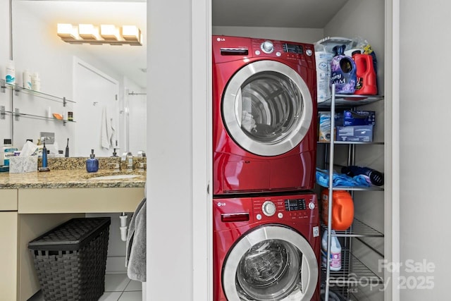 laundry room featuring tile patterned floors, stacked washer and clothes dryer, a sink, and laundry area