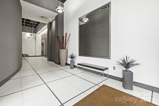 hall featuring light tile patterned floors, visible vents, and baseboards