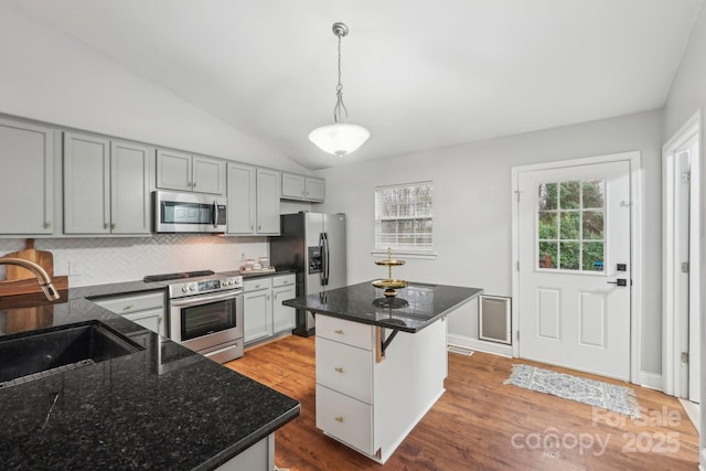 kitchen with lofted ceiling, wood finished floors, a sink, stainless steel appliances, and a wealth of natural light