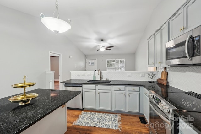 kitchen with a peninsula, stainless steel appliances, a sink, and lofted ceiling