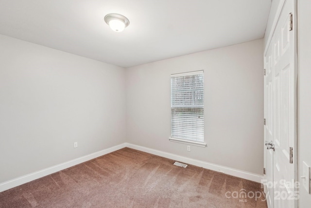 carpeted empty room featuring baseboards