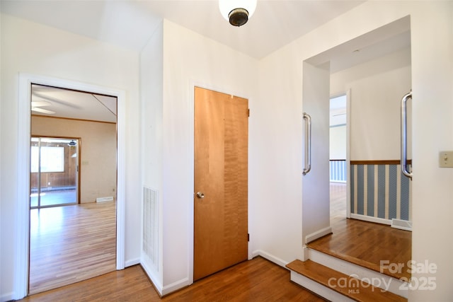 hall featuring visible vents, baseboards, and wood finished floors