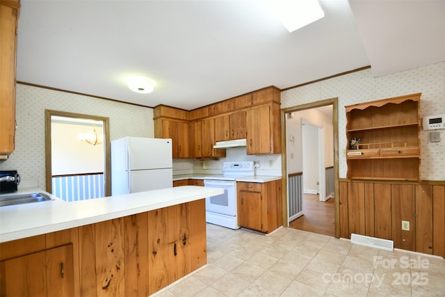 kitchen featuring white appliances, light countertops, under cabinet range hood, and wallpapered walls