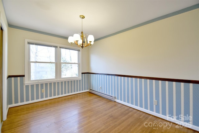 unfurnished room featuring a chandelier, baseboard heating, wood finished floors, and wallpapered walls