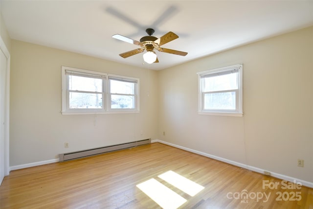 empty room with a ceiling fan, light wood-style flooring, a baseboard heating unit, and baseboards