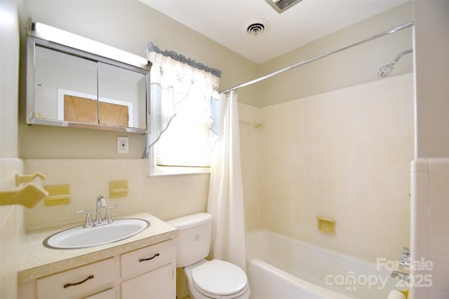 full bath with tile walls, visible vents, toilet, shower / tub combo, and vanity