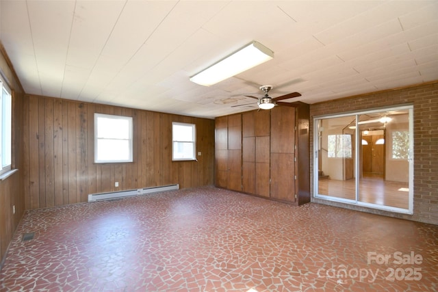 unfurnished room featuring wood walls, a baseboard radiator, and a ceiling fan