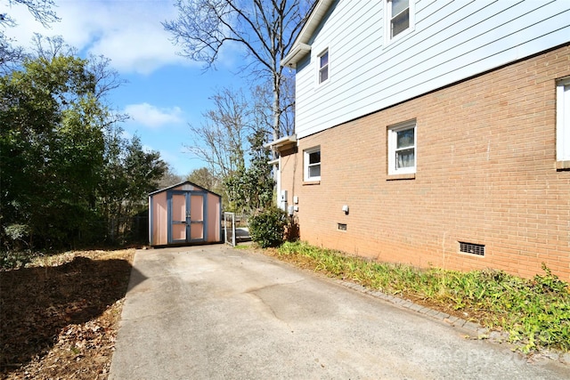 view of home's exterior with an outbuilding, a storage unit, crawl space, and brick siding