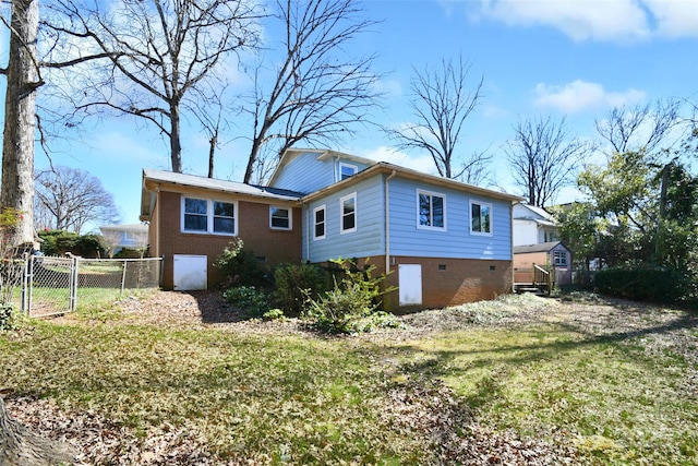 back of house featuring a storage shed, crawl space, fence, a yard, and brick siding