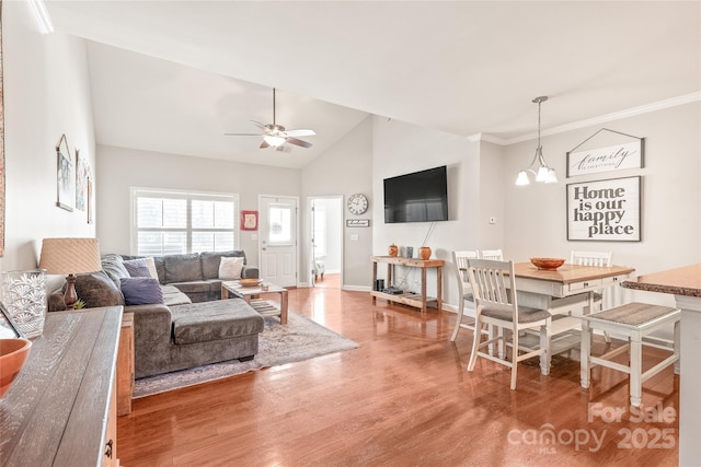 living area with ceiling fan with notable chandelier, wood finished floors, baseboards, vaulted ceiling, and ornamental molding