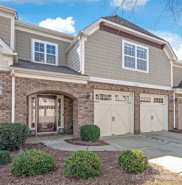 exterior space featuring driveway, brick siding, and an attached garage