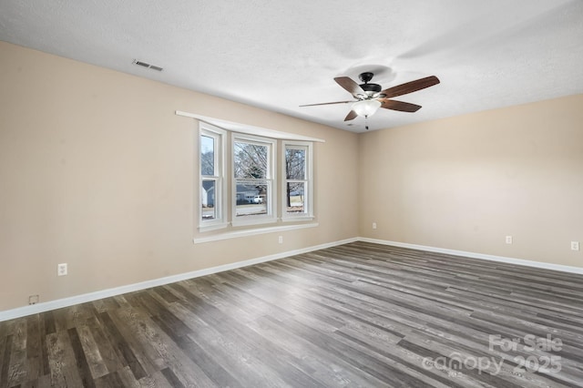 spare room featuring ceiling fan, a textured ceiling, visible vents, baseboards, and dark wood-style floors