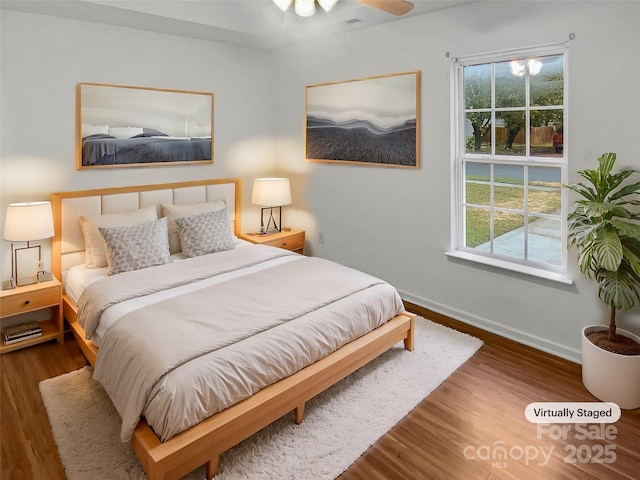 bedroom featuring multiple windows, baseboards, and wood finished floors