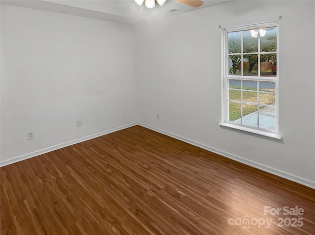 spare room with plenty of natural light, baseboards, and dark wood-style flooring