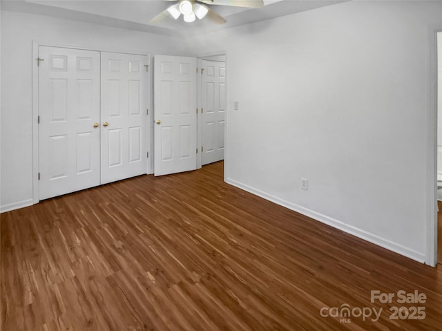 unfurnished bedroom with ceiling fan, a closet, wood finished floors, and baseboards