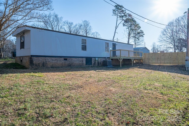 rear view of house with cooling unit, a lawn, a deck, and fence