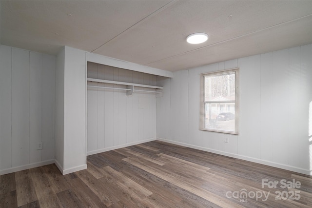 unfurnished bedroom with a closet, baseboards, and wood finished floors