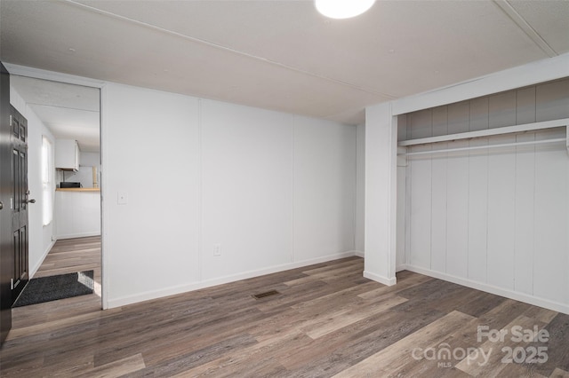 unfurnished bedroom featuring a closet, visible vents, and wood finished floors