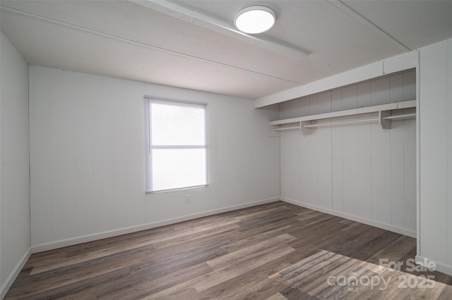 unfurnished bedroom featuring dark wood-style flooring, a closet, and baseboards