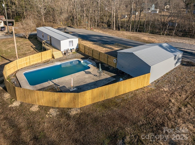 view of swimming pool with a fenced backyard, a fenced in pool, and an outbuilding