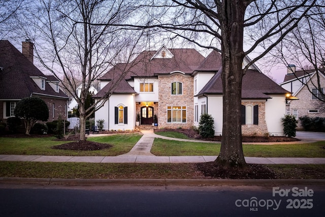 view of front of house featuring stone siding, a front lawn, and stucco siding