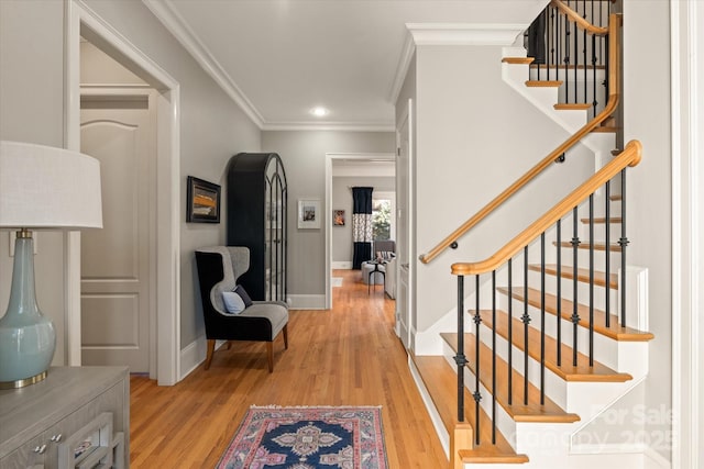 foyer entrance with baseboards, ornamental molding, stairway, and light wood-style floors